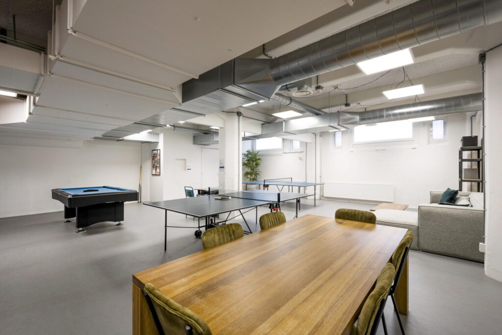 Modern recreation room with a wooden dining table, table tennis setup, pool table, and lounge area in Van Diemenstraat.
